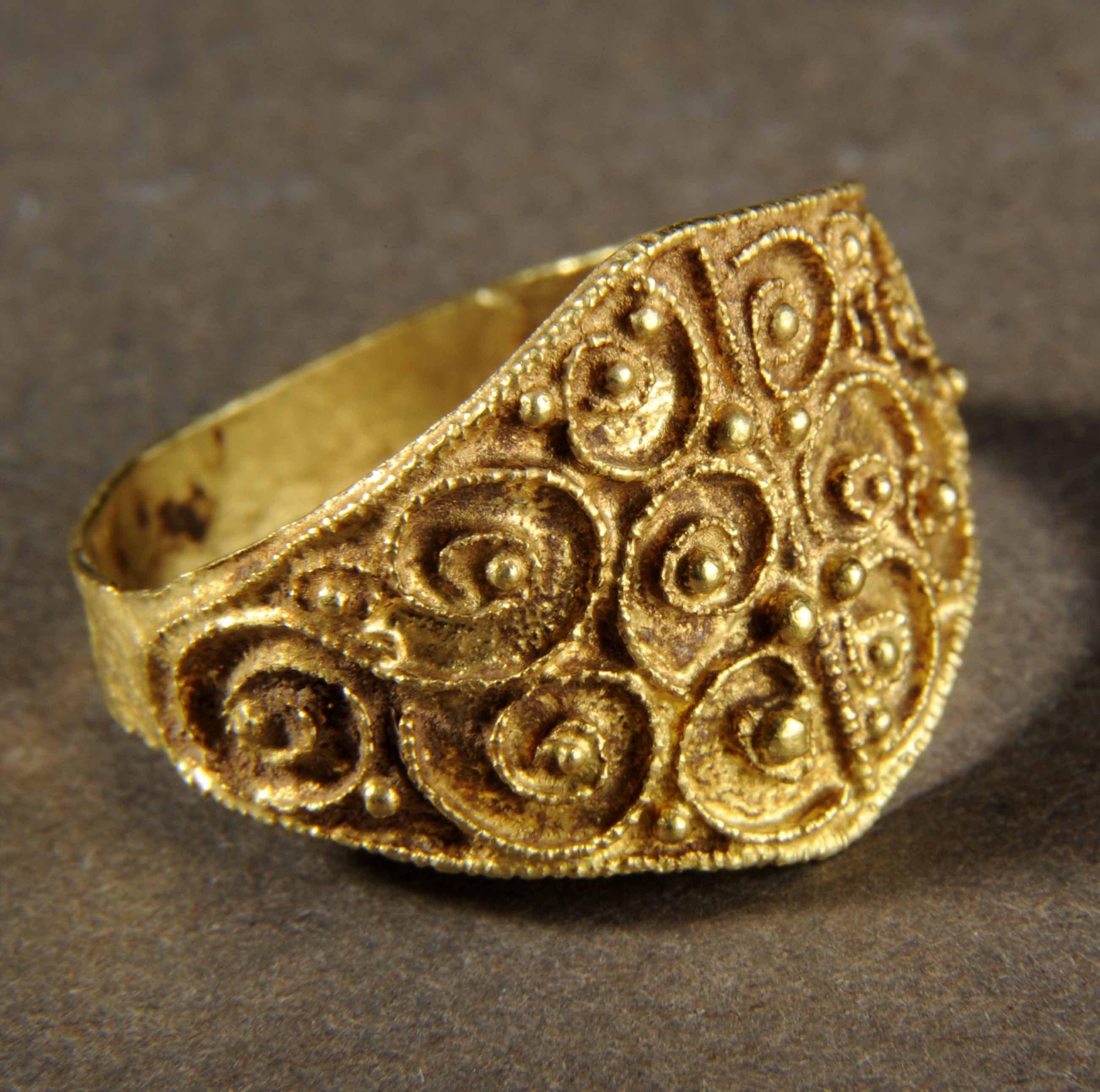 Medieval gold ring with detailed filigree design or swirls and small gold balls.
