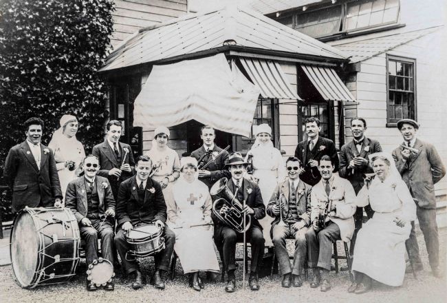 Black and white photo of band members with their instruments, including drums, trumpets, flute and tambourine.
