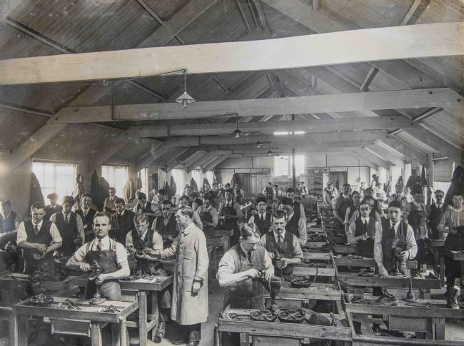 Black and white photograph showing blinded ex-servicemen assisted by St Dunstan's (now Blind Veterans UK) learning to repair boots.