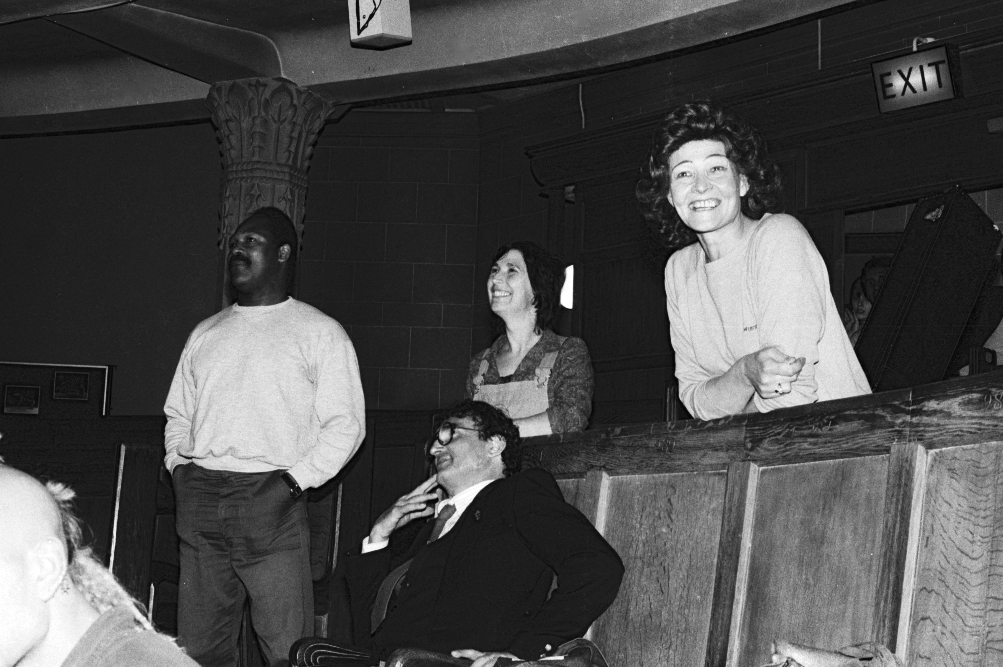 Black and white photo showing Nadine Senior leaning on theatre seats, with others