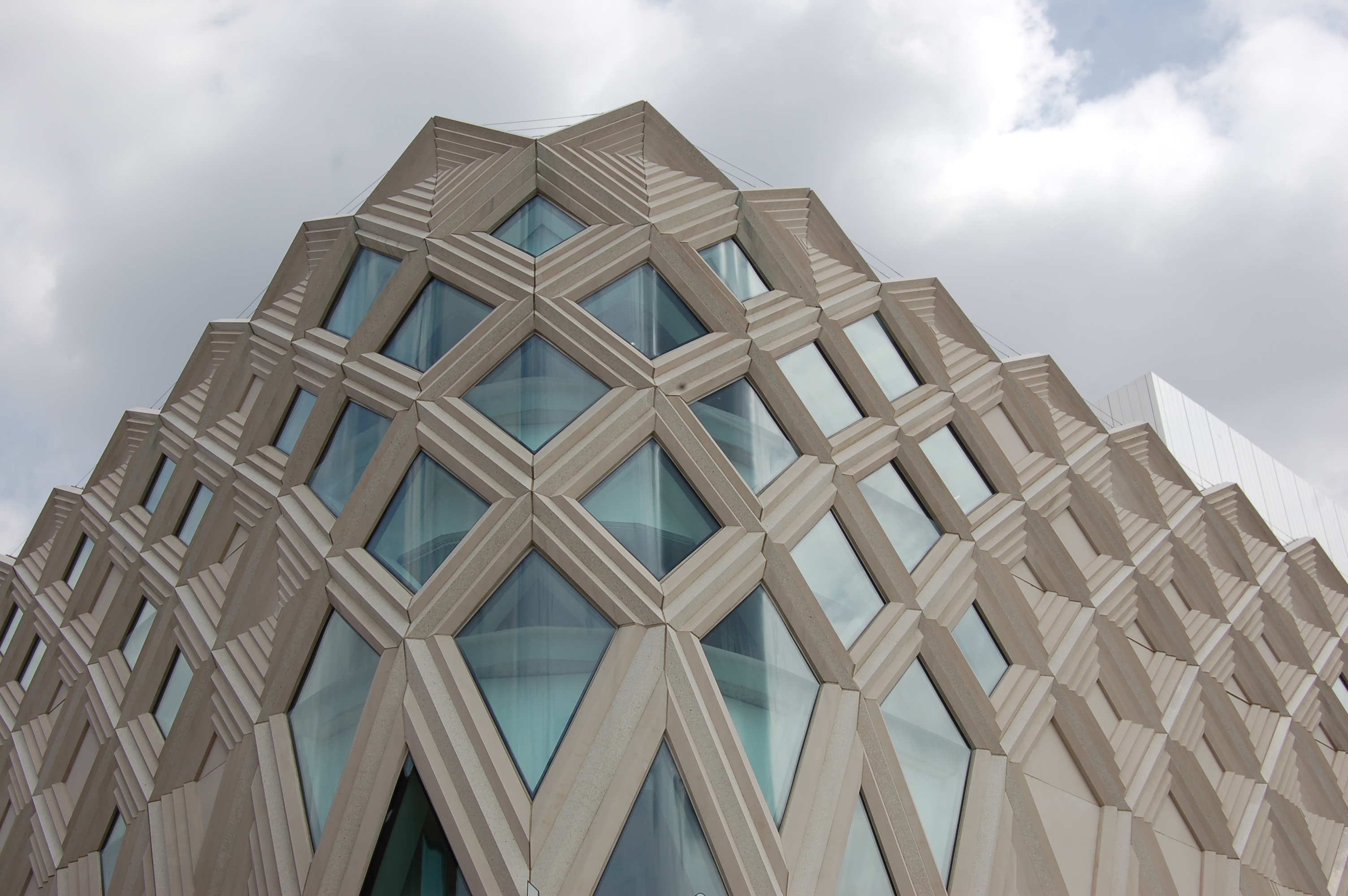 Contemporary photograph of part of a building with diamond shaped windows with pale stone surround.