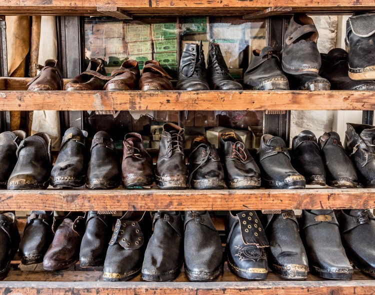 Colour photograph of three shelves of Edwardian clogs, in all different sizes and various designs