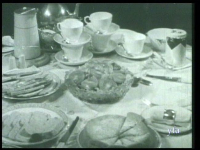 Tea table with bread, tomatoes, cake and tea cups on it