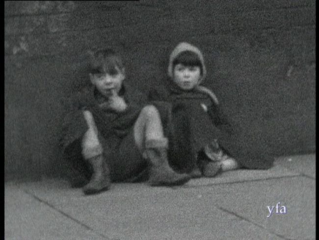 Black and white film still of two young boys sitting in a Hull street in 1950