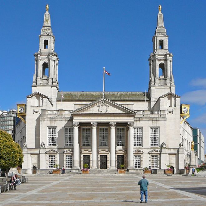 Leeds Civic Hall is made of white coloured stone, with a steeple either side of a columned front entrance.  on top of each steeple is a gold owl and a gold clock is fixed to each side of the Hall.