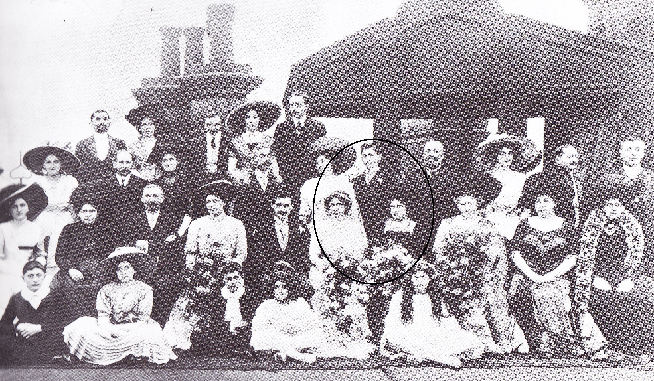 Black and white photo of wedding party dressed in suits, dresses, hats etc