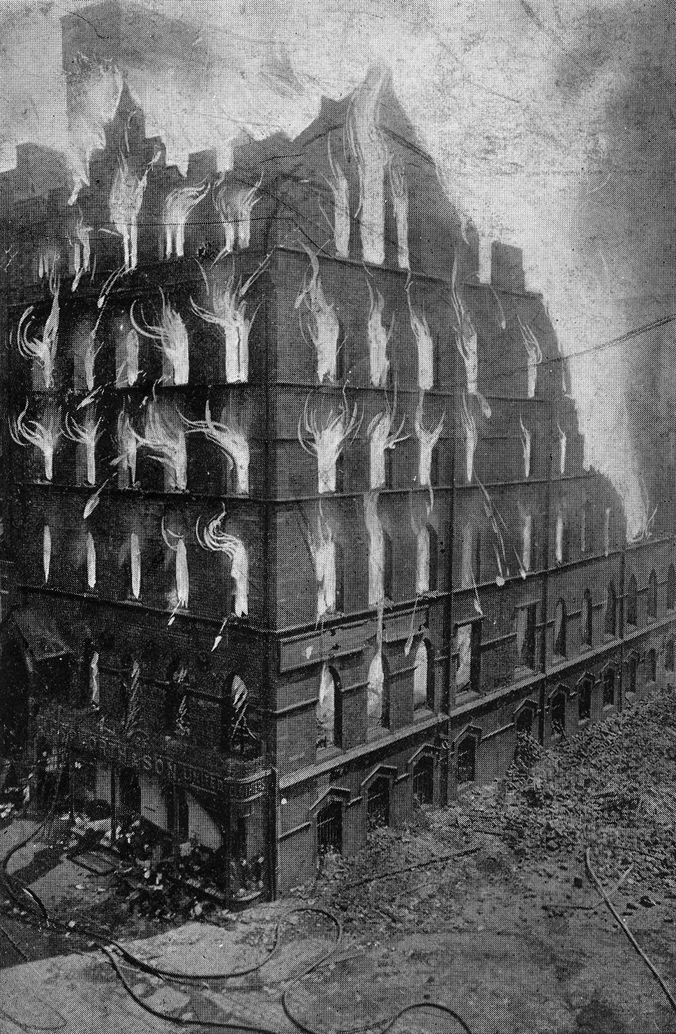 Postcard showing flames pouring out of windows of large 4 storey building