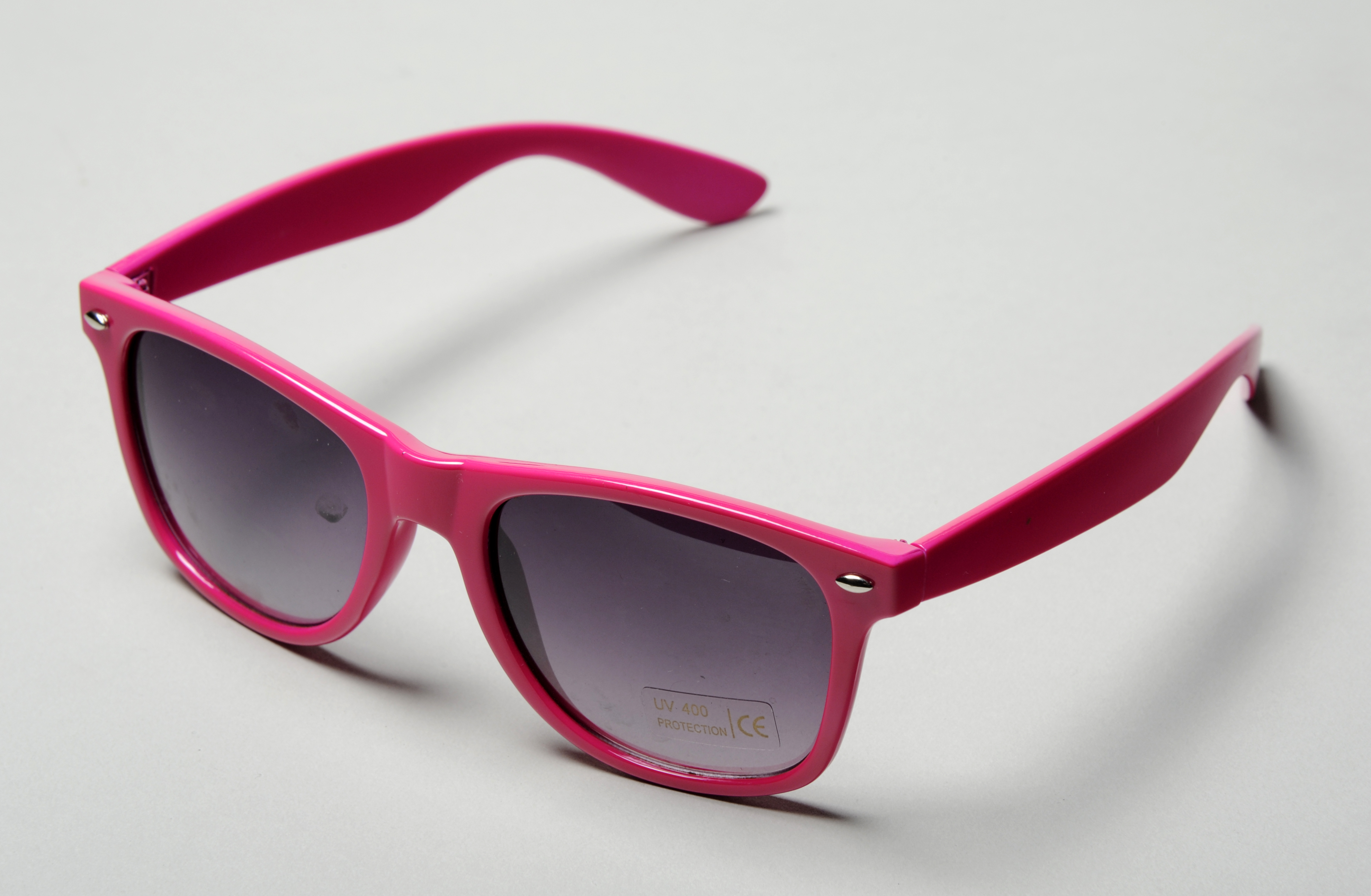 Colour photograph of a pair of pink plastic sunglasses