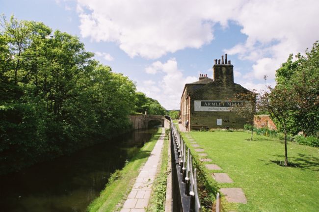 Side on view of a mill building, showing it parallel to a canal.