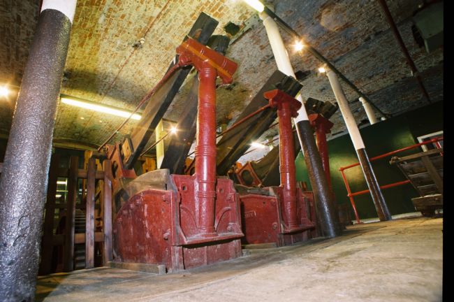 Large scale heavy machinery with heavy 'hammer' on a pin that enables it to move up and down to pound the cloth.