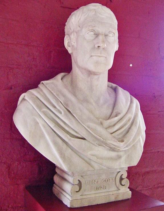 Classical style marble bust of a man shown wearing material draped over his shoulders.