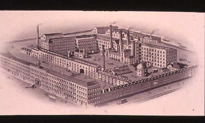 black and white shaded drawing showing a big mill complex arranged in a square with multiple buildings and chimneys inside the perimeter.