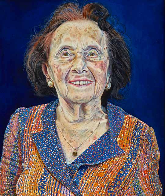 The image is a vibrant, detailed portrait of an elderly woman with short, wavy hair. She is wearing a colorful, patterned jacket in shades of orange, blue, and red. The woman has a warm, bright smile, and her expression is full of life and positivity. Her skin is depicted with great detail, showing the natural textures and markings of age. She is also wearing earrings and a small pendant necklace. The background is a deep, rich blue, which contrasts beautifully with her bright clothing, making her figure stand out prominently in the portrait. The overall mood of the painting is lively and celebratory, capturing the woman's joyful spirit.