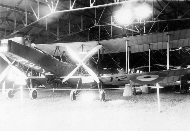 Black and white photograph of early aircraft.  It is a bi-plane and has a single propeller with four blades on the front.