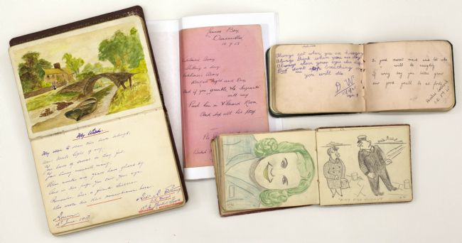 Photograph of four open WW1 autograph books showing sketches and a watercolour painting