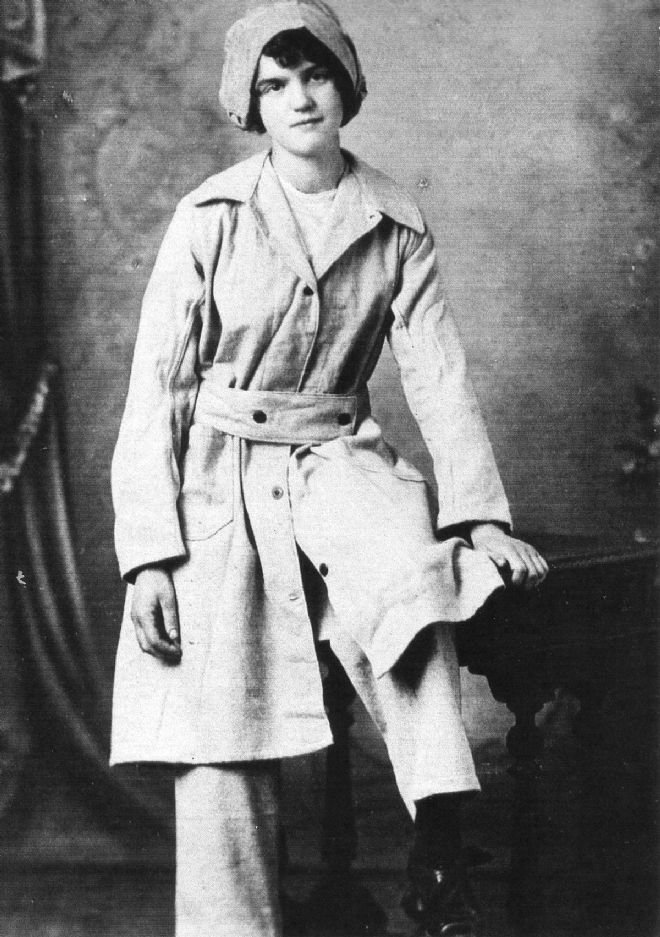Black and white photograph of female factory worker in overalls and hat