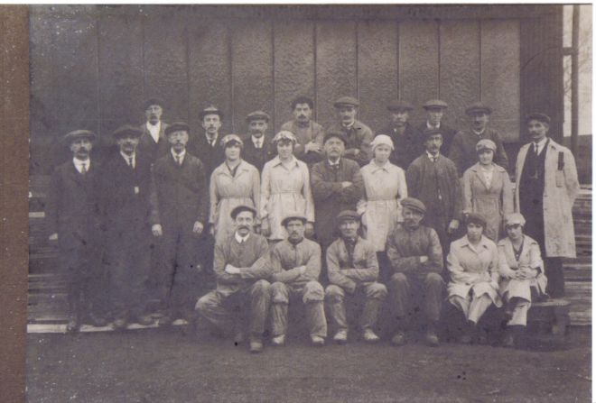 Group photograph of male and female factory workers outside the factory