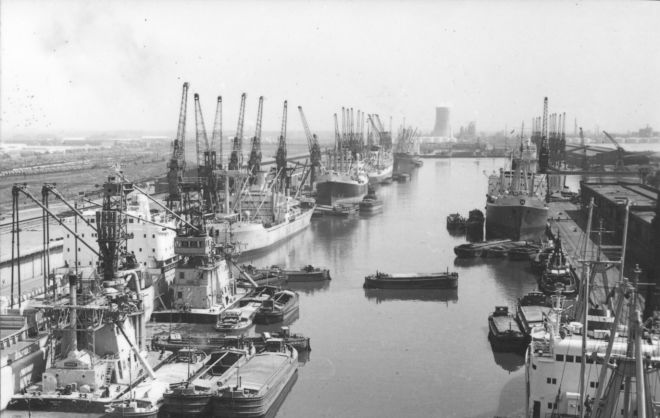 Black and white photograph of Hull's docks, with boats and barges docked and many cranes