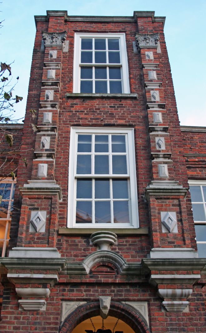 the house is made of red brick, with stoen carvings.  It is three stories high with large sash windows.