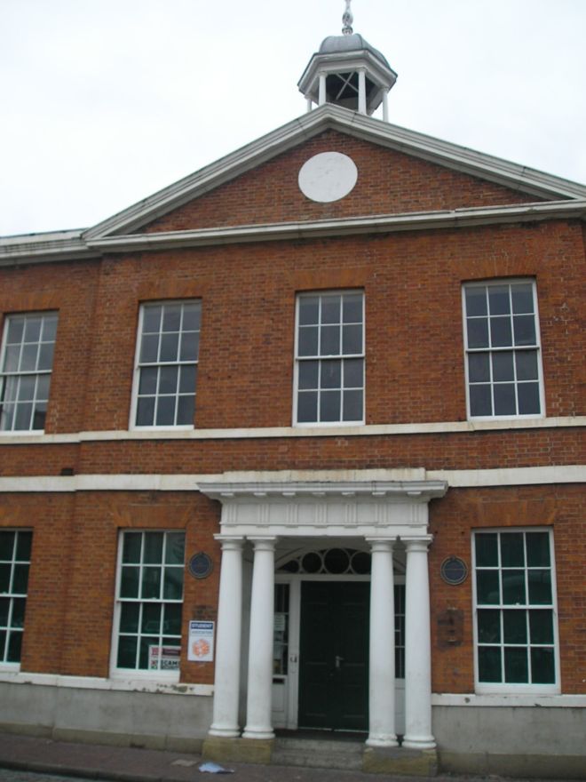 Red brick building with a central doorway flanked by pillars