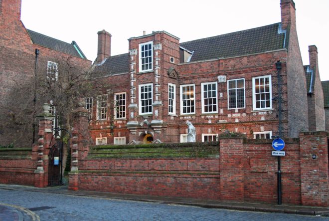 Red brick house with sa chimney at each end and large sash windows along the length.