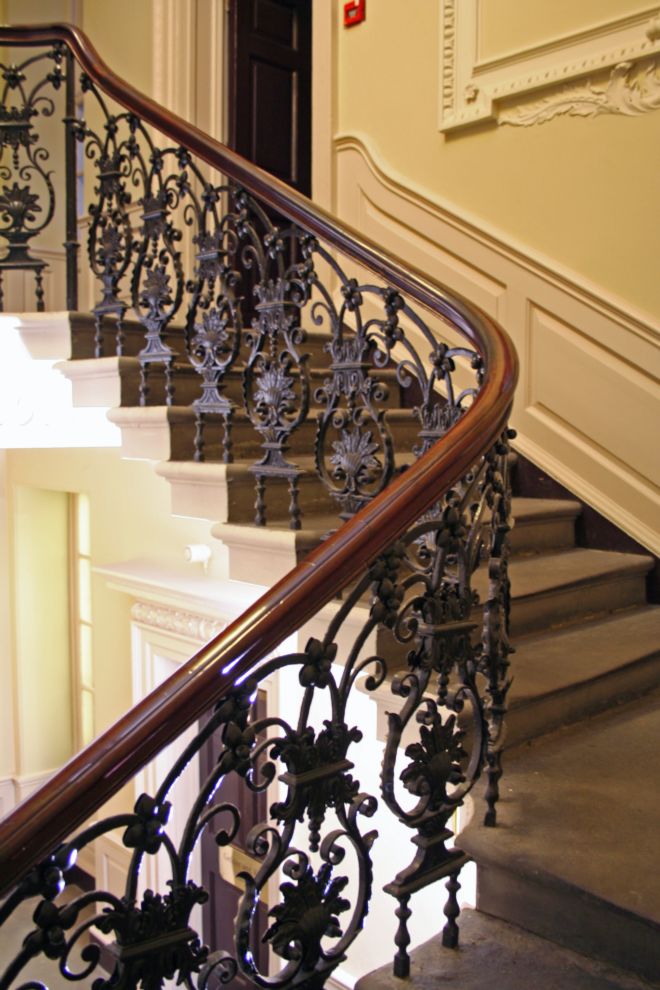 Stone staircase with beautiful wrought iron balustrade in the shape of flowers and other designs.