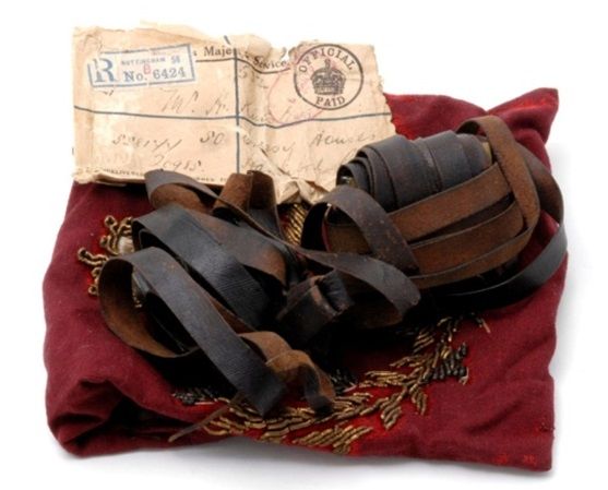 Small leather pouch with long leather straps on  a dark red piece of material.