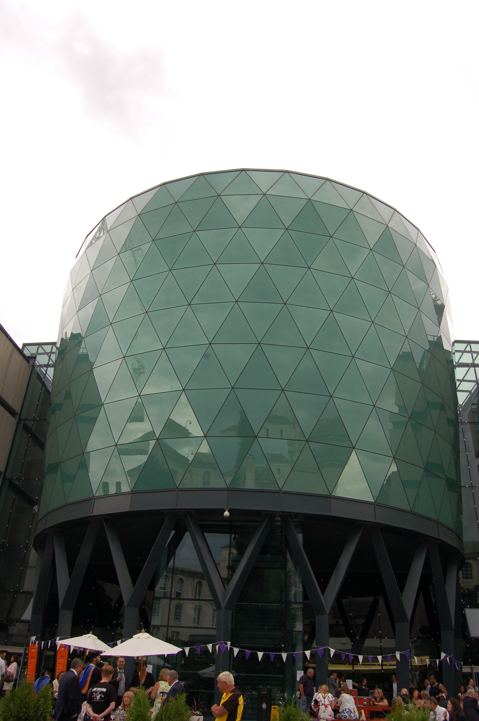 Contemporary photograph showing a circular glass building composed of tessellating triangles.