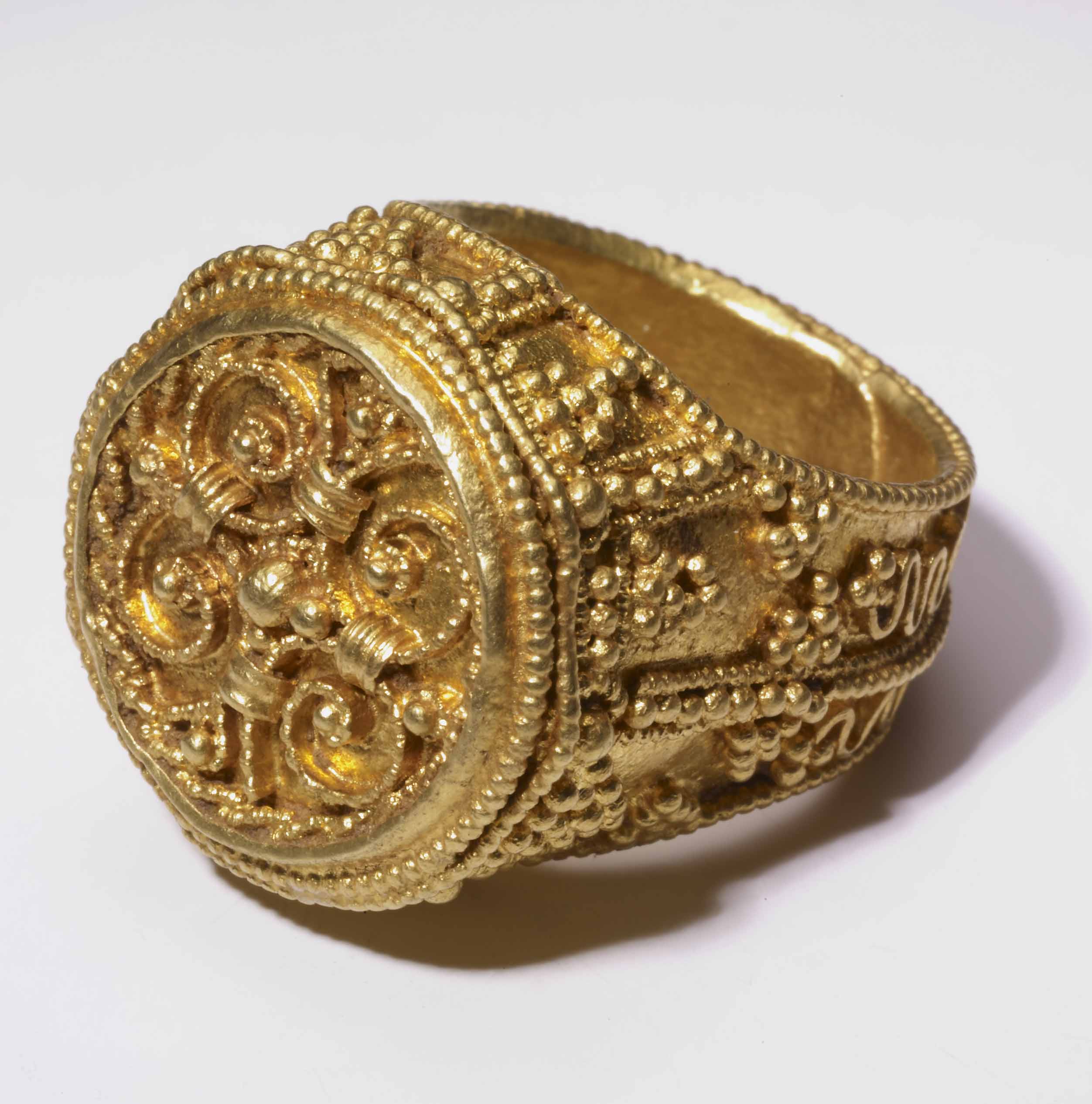 Medieval gold ring with circular face and detailed filigree design.
