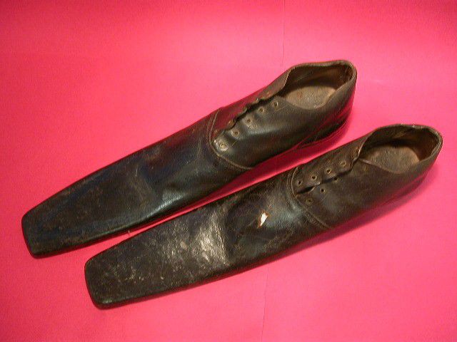 Leather lace up shoes with very long front parts that stick out about the same length of the actual shoe part, a bit like very narrow diving fins.