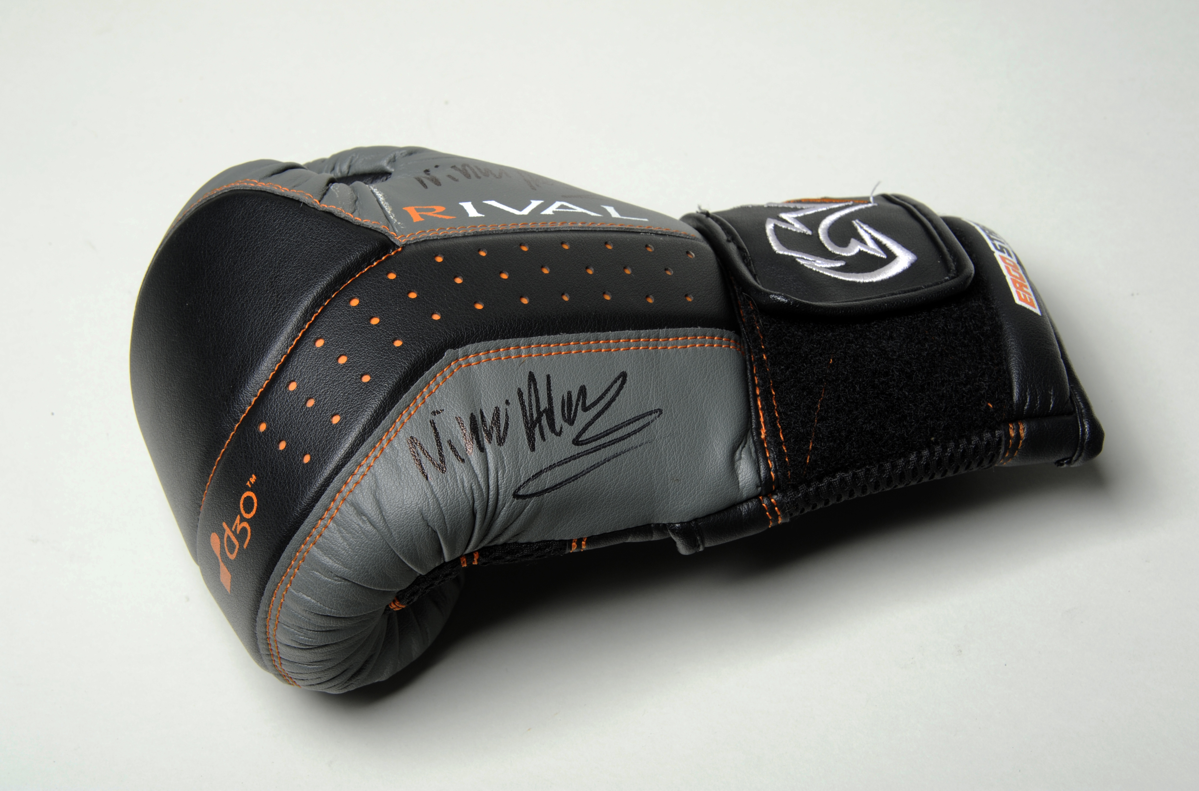 Colour photograph of a black and grey boxing glove. It has Nicola Adams' signature on the side of it written in black sharpie