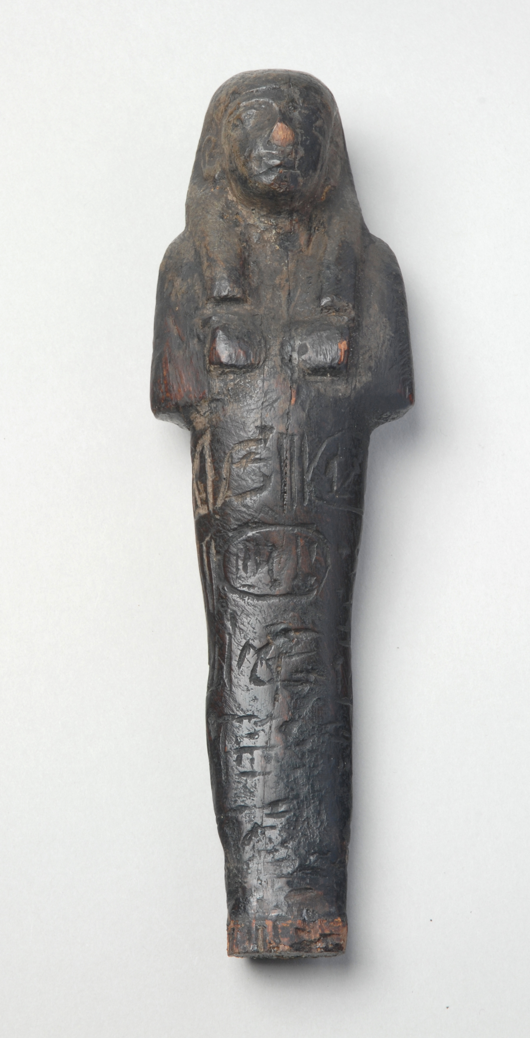 Colour photograph of a molded figurine in the shape of a person with hieroglyphs carved on it
