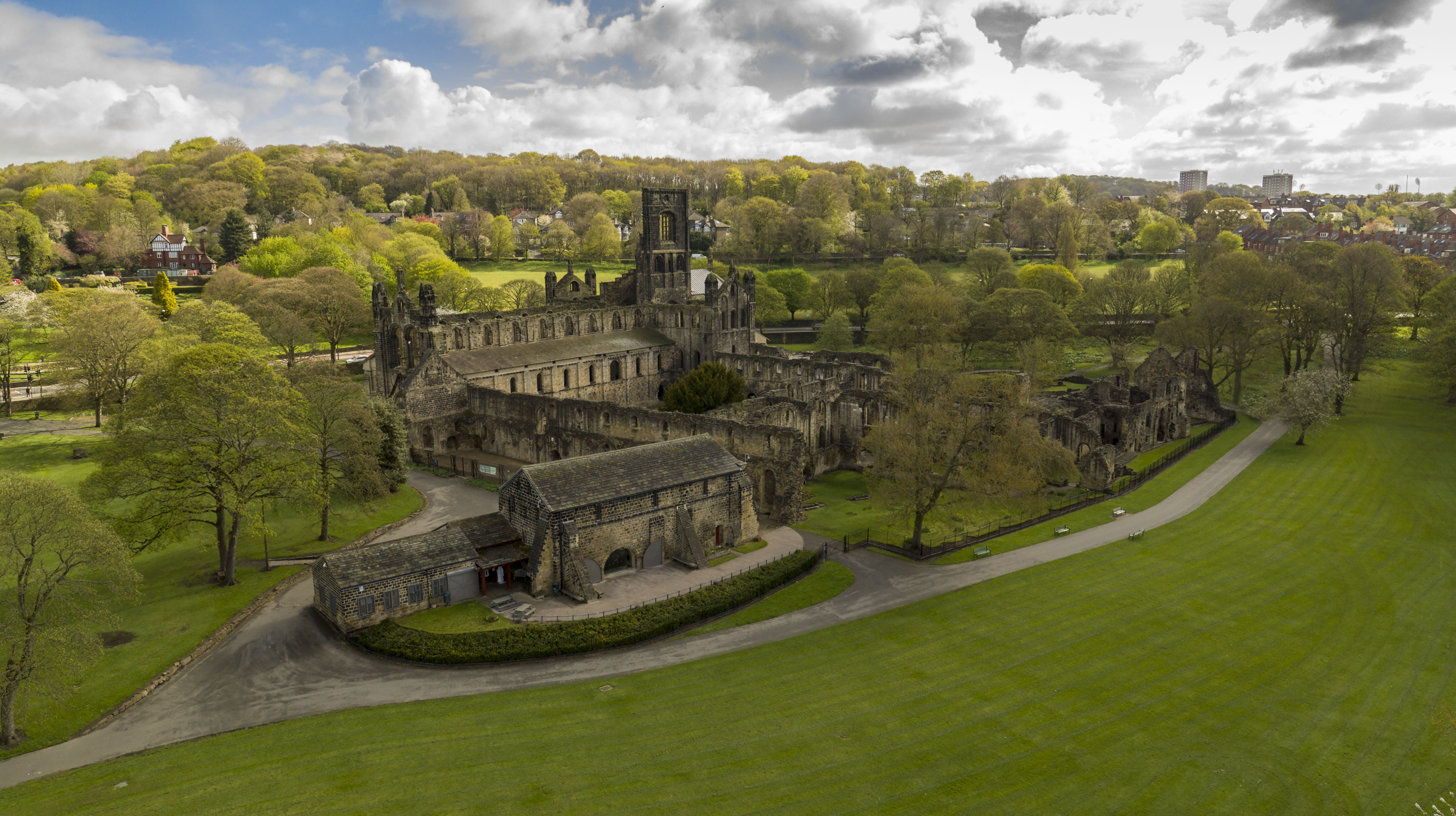 Colour photograph of the remains of a medieval abbey with bluebells in the foreground