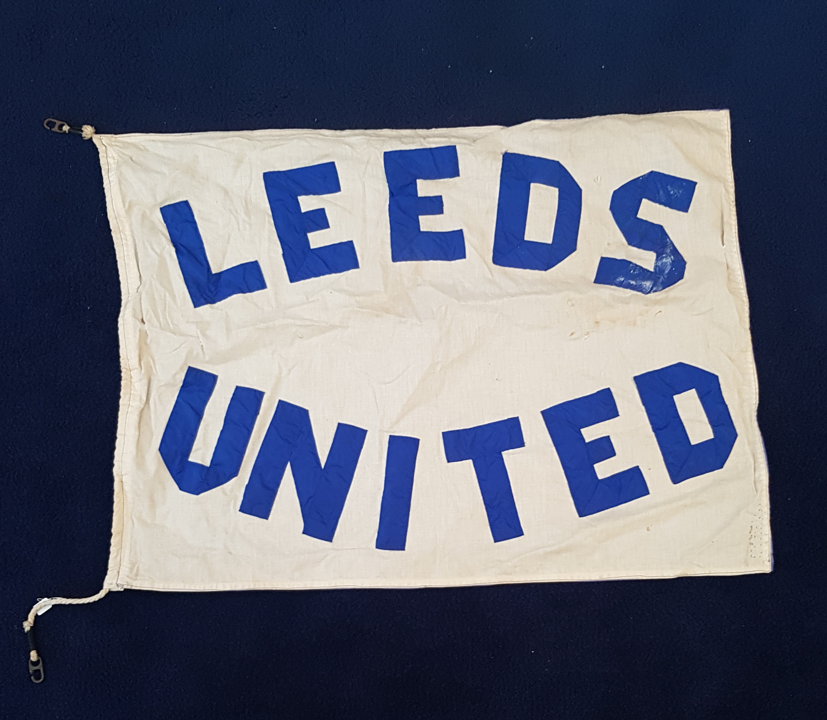 White flag with blue lettering that says 'Leeds United'