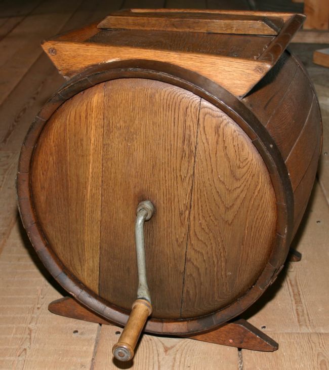 A  wooden circular box with a square opening on top and a handle on one end which you turned to churn the milk into butter.