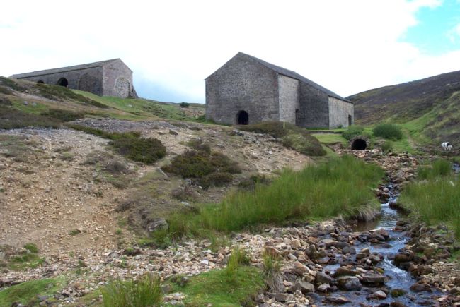 Stone building at the top of a valley with stream flowwing in the forground.