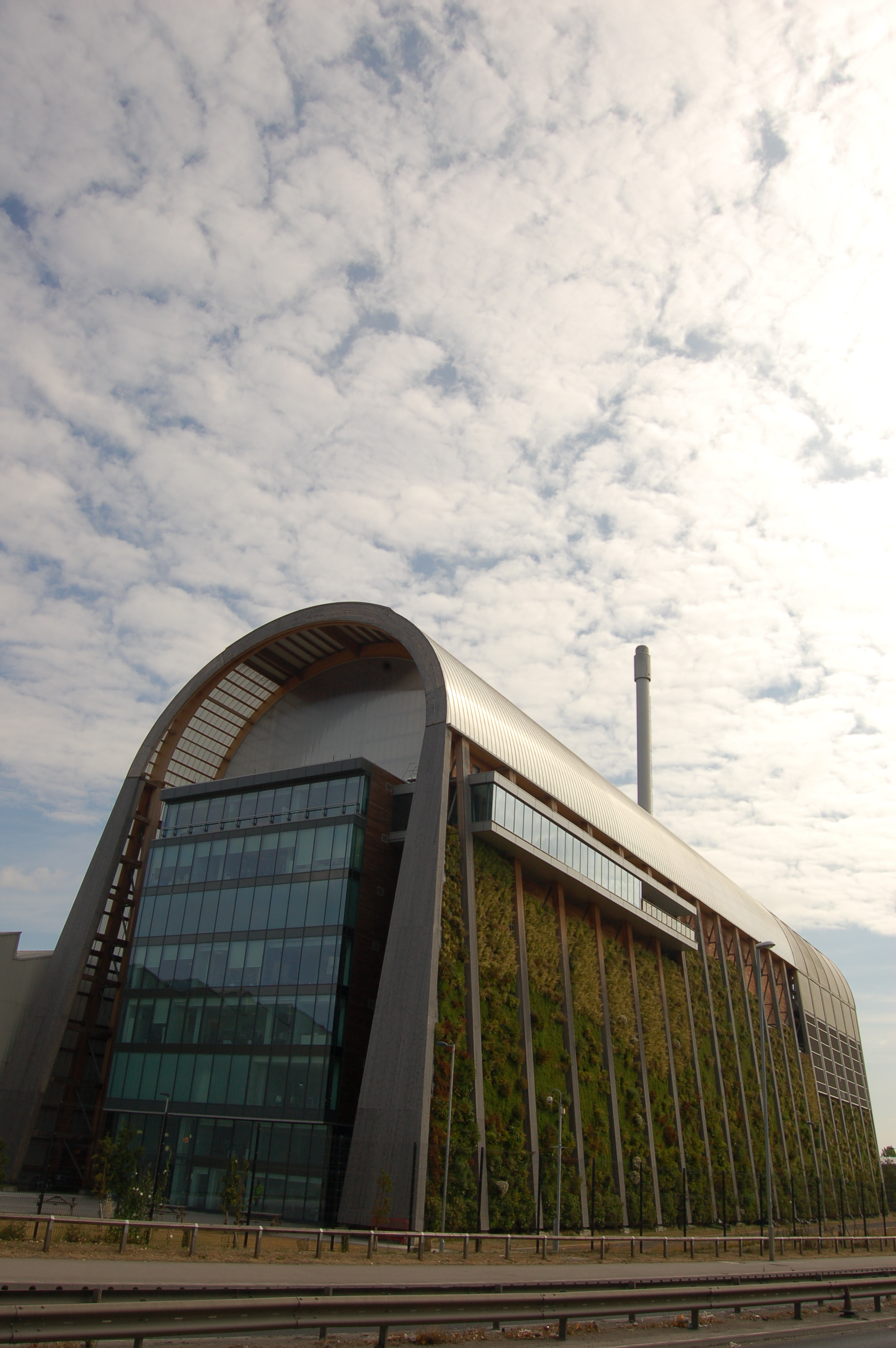 Contemporary photograph of a building in the shape of an upside down 'U', with plants growing up all one side of the wall.