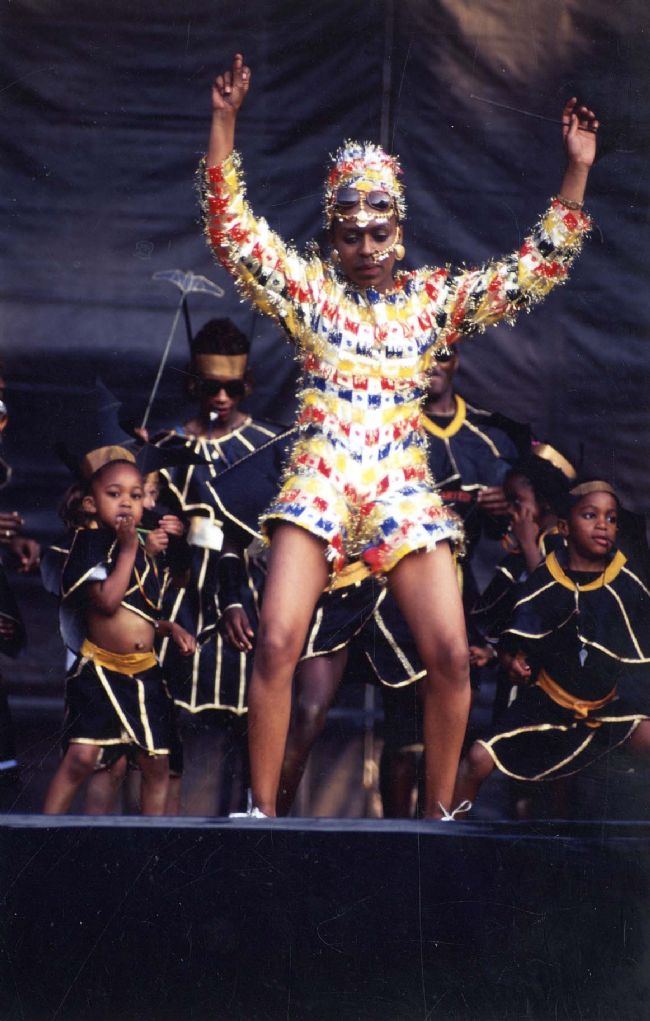 Woman in a colourful carnival one-piece costume with longsleeves and shorts with matching hat.