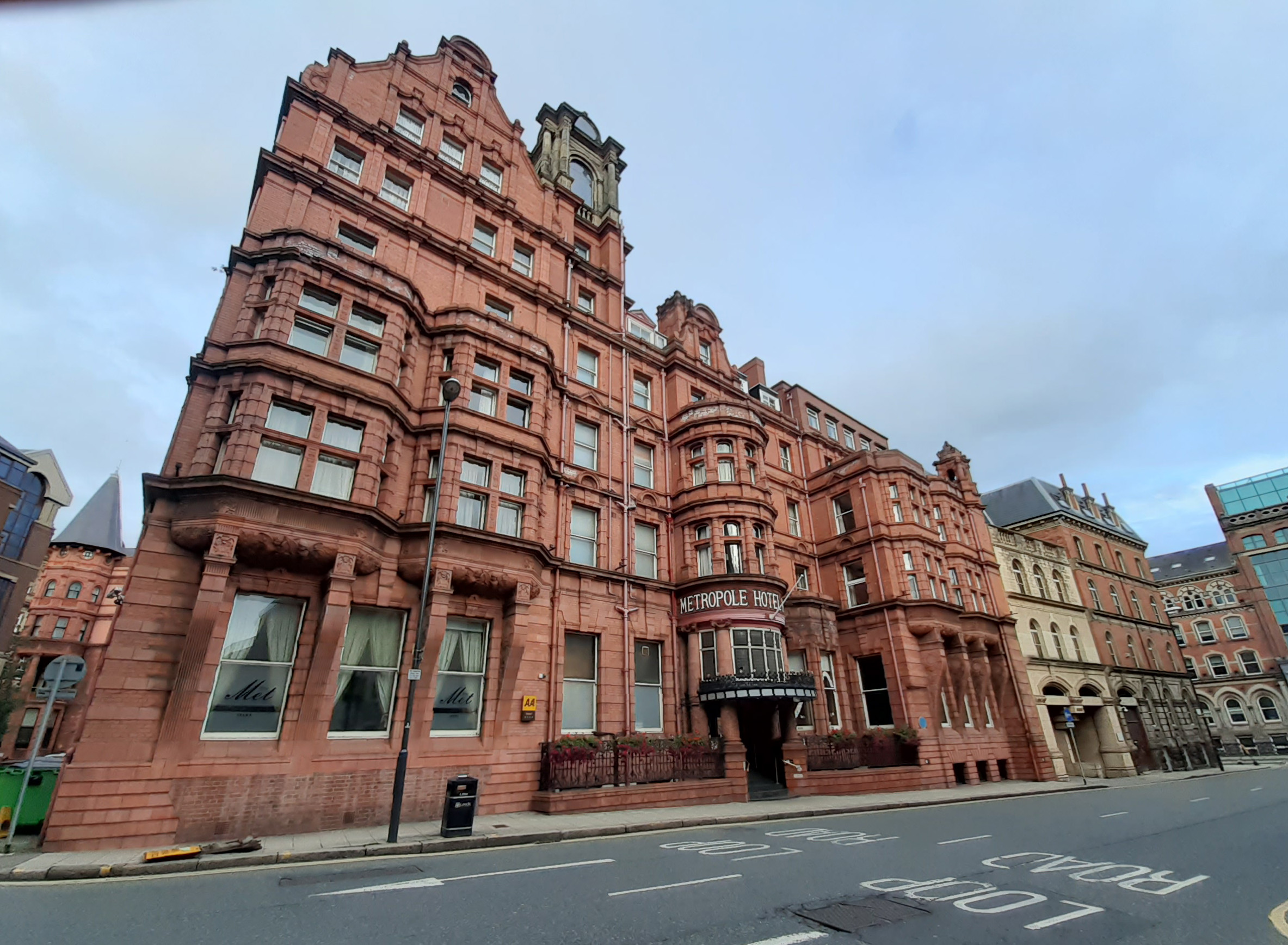 Colour photograph showing a large red brick building with protruding windows and a gothic style