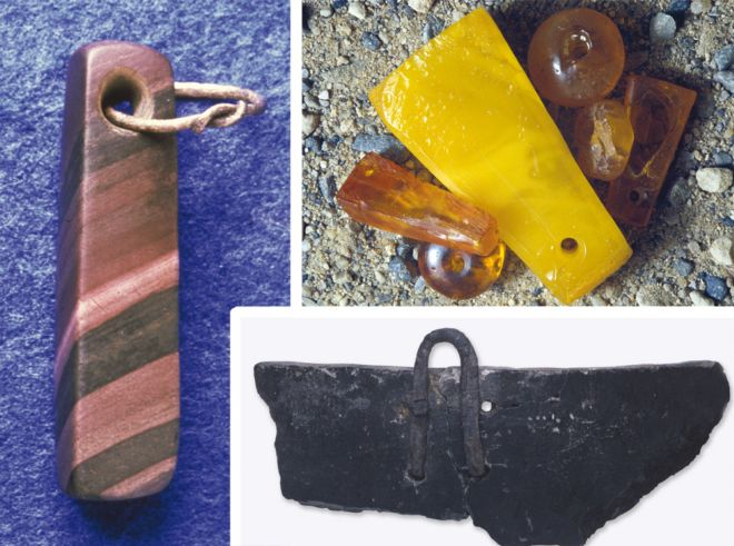 On the left is a shaped and smoothed striped stone in brown, beige and black.  A hole has been drilled in one end and holds a metal hoop.  Top right are pieces of amber, ranging from dark yellow to dark orange.  Bottom right is a shard of a bowl.  it is black in colour and has a metal loop in it.