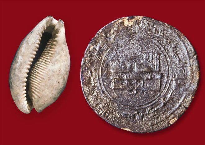 Cowrie shell and coin are about the same size.  The coin is very worn and the inscriptions and pictures are difficult to see.