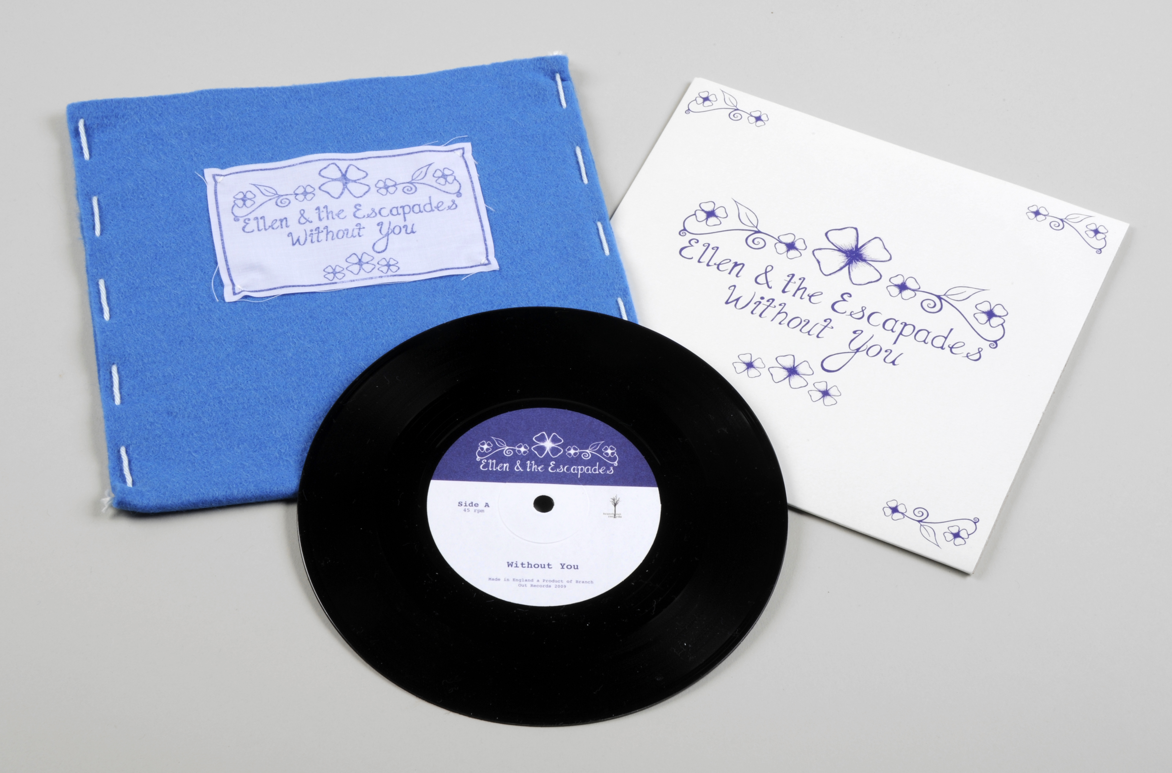 Colour photograph of a vinyl record, a blue felt sleeve and a printed white inner sleeve.