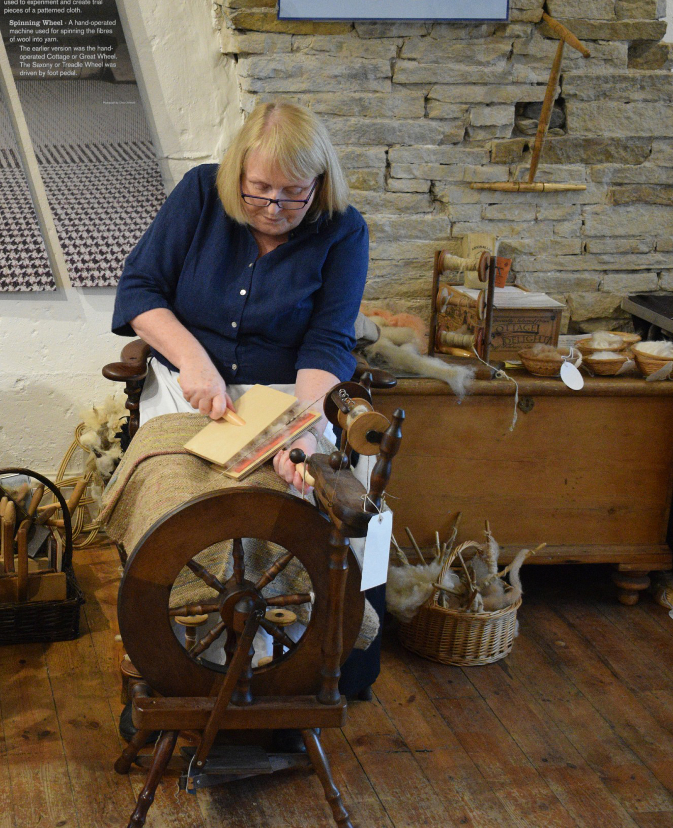 Lady working with wooden paddles to tease wool ready for spinning