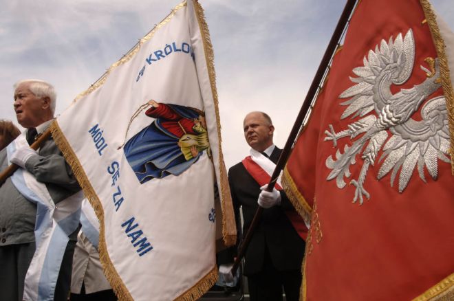 Two men are marching, each holding a large flag