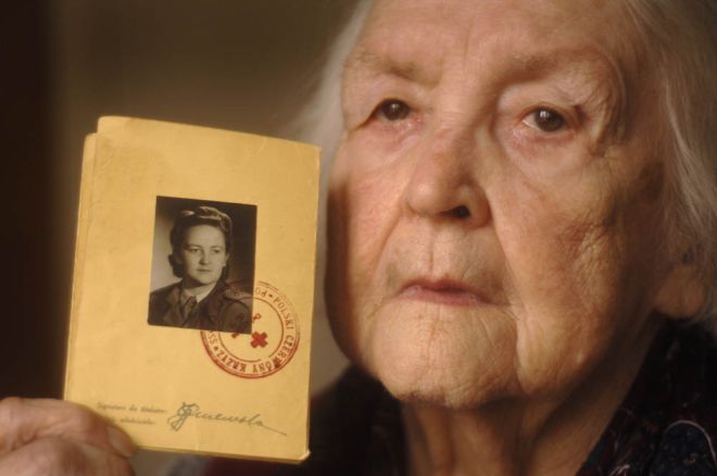 An elderly Polish woman holds a photograph of herself in Polish Air Force uniform