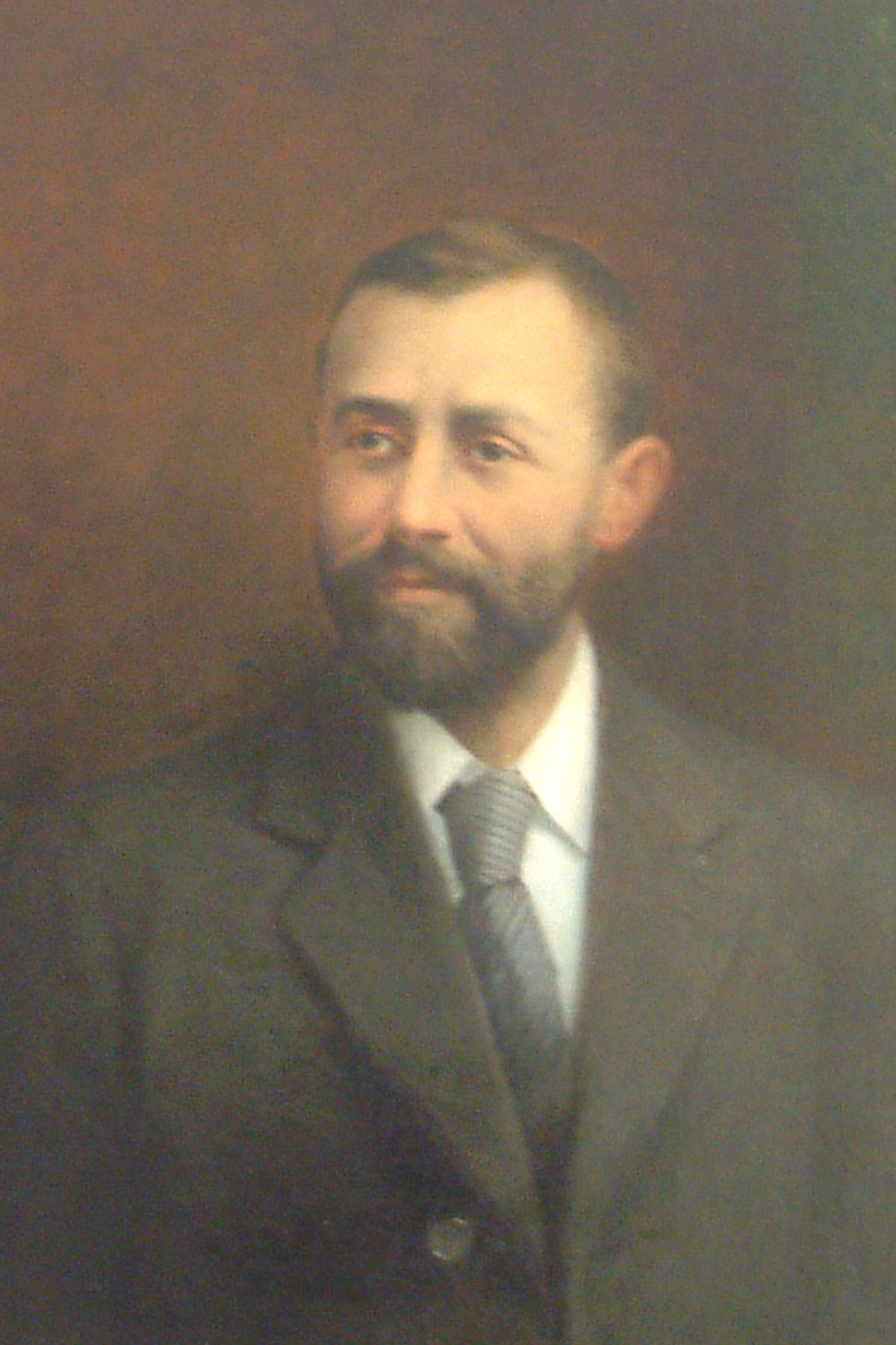 Colour photo of an oil painting portrait of a bearded gentleman wearing a suit and tie