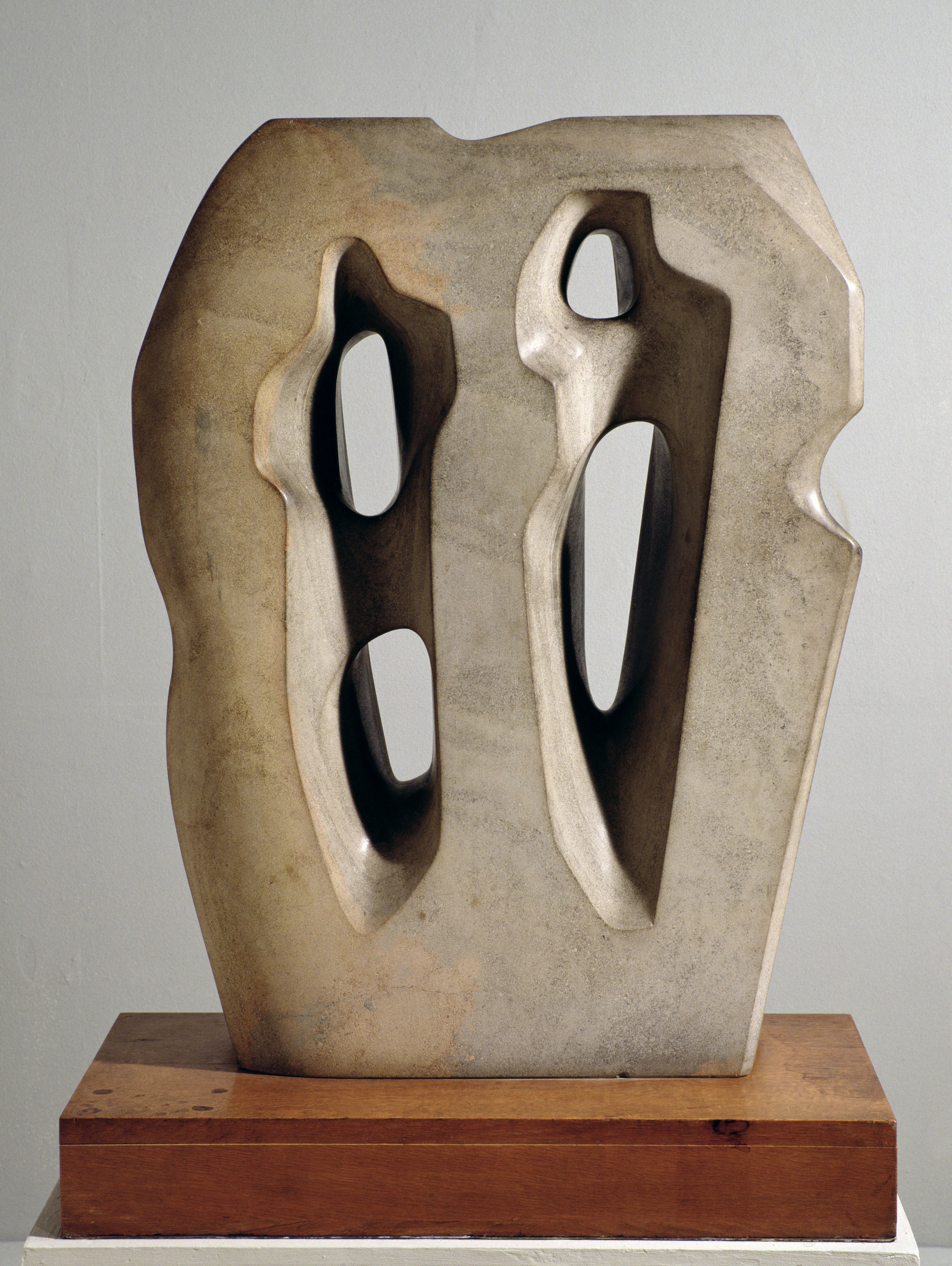 Hieroglyph by Barbara Hepworth, a stone sculpture slightly wider at the top than the bottom, with movement lines upwards and four, unequal holes through the stone