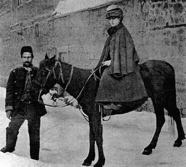 Black and white image of Isabella Bird on a pony near a wall.  There is a Tibetan man holding the reins of the pony