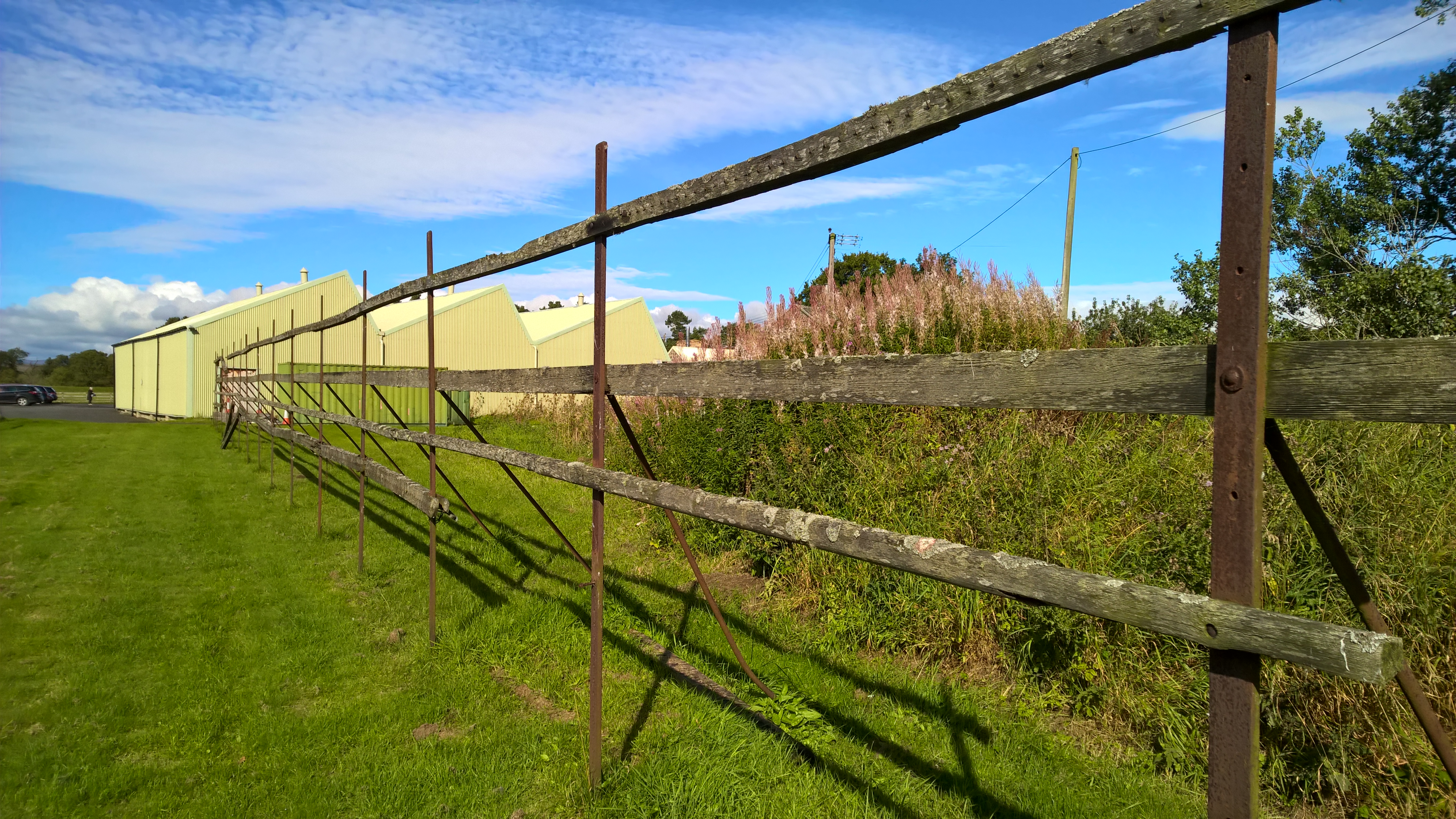 Wooden frames in a field.  Metal hooks can be seen along the top bar of the frame.