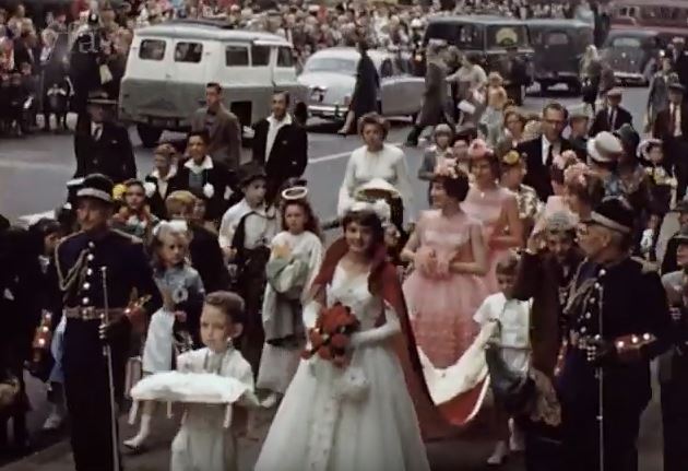 Colour film still showing a parade down a street in Leeds